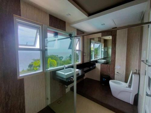 een badkamer met een wastafel, een toilet en een raam bij The Lighthouse in Puerto Galera