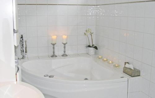 a white bath tub with two candles in a bathroom at Stunning Home In Huskvarna With 3 Bedrooms And Wifi in Huskvarna