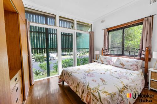 a bedroom with a bed and large windows at Luka House in Iluka