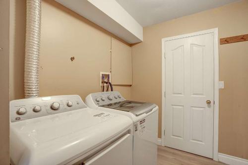 eine Waschküche mit einer weißen Waschmaschine und einem Trockner in der Unterkunft Beautiful 3-bedroom Suite on 1 Acre in Maple Ridge District Municipality