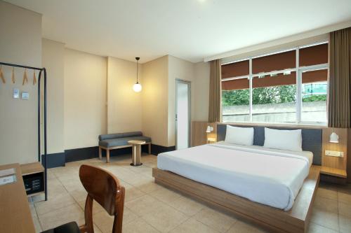 1 dormitorio con 1 cama blanca grande y 1 silla en Liberta Hub Blok M Jakarta, en Yakarta