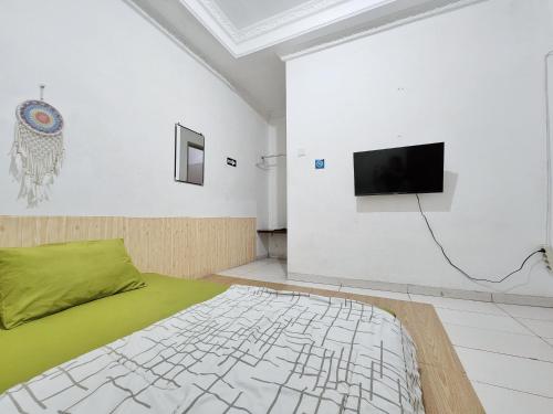Habitación con cama y TV en la pared. en Homey Guesthouse Kertajaya (Syariah) en Surabaya