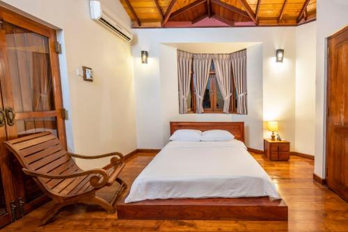 ein Schlafzimmer mit einem Bett und einem Holzstuhl in der Unterkunft Kalugal Nivasa in Colombo