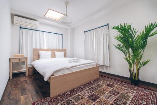 a bedroom with a bed and a potted plant at Nippori Fabric Hotel in Tokyo
