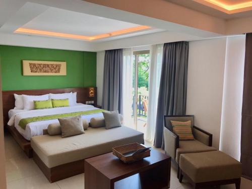 a bedroom with a king sized bed and a chair at d'primahotel Petitenget Seminyak 2 in Seminyak