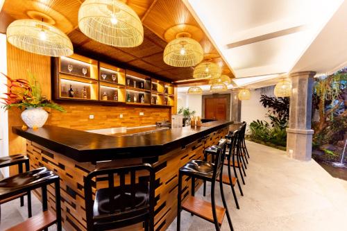 a kitchen with a bar with chairs and chandeliers at Anumana Village Ubud in Ubud