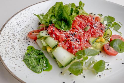 a white plate of food with vegetables and sauce at Anumana Village Ubud in Ubud