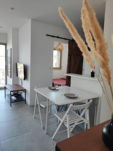 une salle à manger avec une table et des chaises blanches dans l'établissement T2 vue mer, à Six-Fours-les-Plages