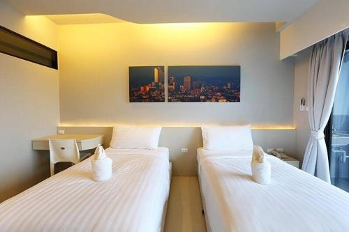 two beds in a room with a view of a city at Hatyai Signature Hotel in Hat Yai