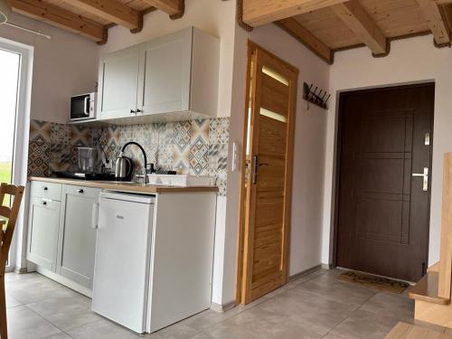 a kitchen with white cabinets and a door to a room at Domki Pod Gwiazdami in Władysławowo