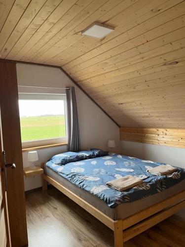 a bedroom with a bed with a wooden ceiling and a window at Domki Pod Gwiazdami in Władysławowo