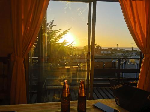 dwie butelki piwa siedzące na stole przed oknem w obiekcie Arriendo casa vista al mar w mieście Las Cruces