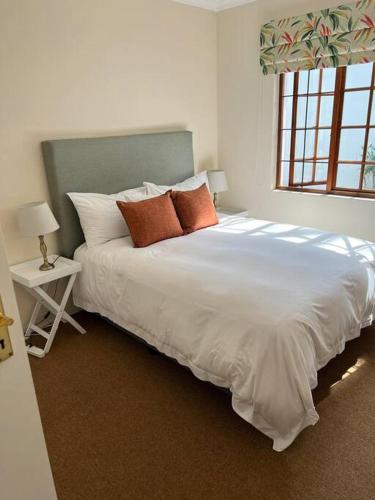 a bedroom with a large white bed with orange pillows at Charming cottage in lush Melrose Garden in Johannesburg