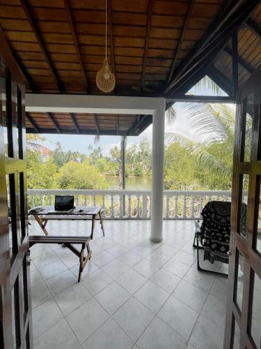 a screened in porch with a table and a view at Shanon Lake Villa Surf Lodge in Midigama