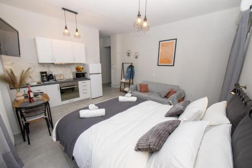 a bedroom with a large white bed and a kitchen at Celestina Corfu Town Apartment in Corfu