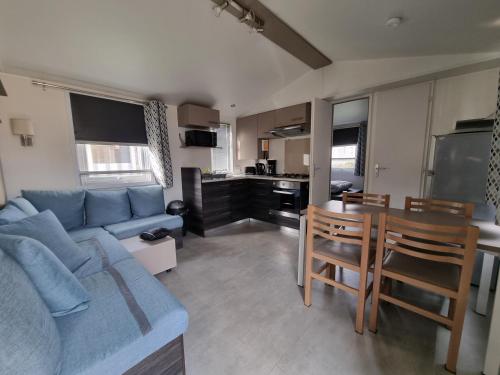 un salon avec un canapé bleu et une table dans l'établissement Joli mobil home 4-6 personnes 416, à Saint-Jean-de-Monts