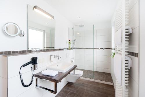 a white bathroom with a sink and a toilet at Hotel Restaurant Bullerdieck in Garbsen