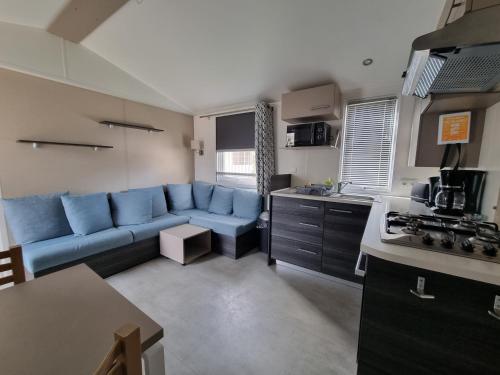 un salon avec un canapé bleu et une cuisine dans l'établissement Joli mobil home 4-6 personnes 416, à Saint-Jean-de-Monts