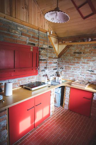 a kitchen with red cabinets and a brick wall at Glamping na podeželju in Lutverci