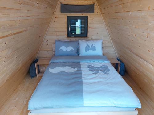 Ce lit se trouve dans une cabine dotée d'un mur en bois. dans l'établissement Glamping na podeželju, 