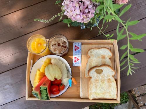 a tray of food with a plate of fruit and bread at Sungsim Hanok Guesthouse in Jeonju