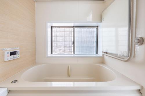a white bath tub in a bathroom with a window at Dat's house in Tokyo