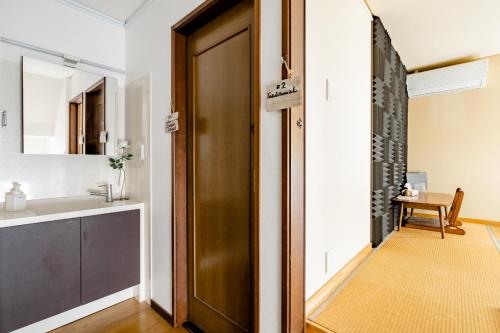 La salle de bains est pourvue d'une porte marron et d'un lavabo. dans l'établissement Dat's house, à Tokyo