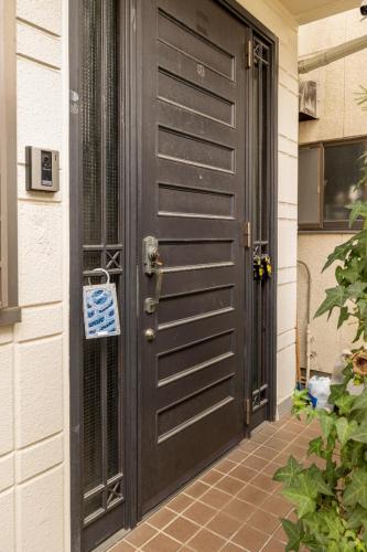 a black door of a house with a sign on it at Dat's house in Tokyo