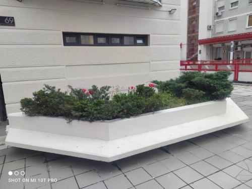 a white bench with plants in it next to a building at Biblioteka Spa Suite in Novi Beograd