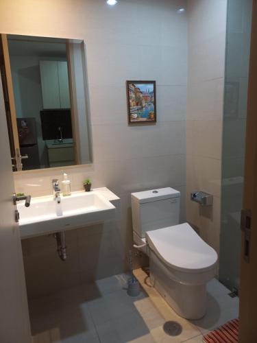 La salle de bains est pourvue de toilettes, d'un lavabo et d'un miroir. dans l'établissement Sedayu City Apartment Studio Tower Melbourne, à Jakarta