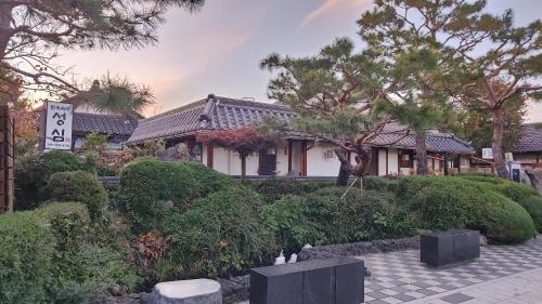 ein Haus mit Bäumen und Büschen davor in der Unterkunft Sungsim Hanok Guesthouse in Jeonju