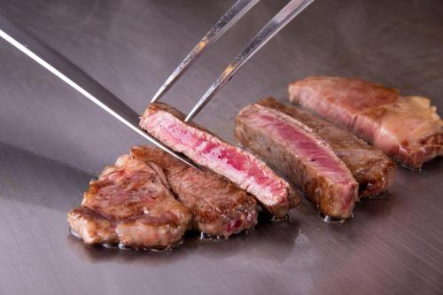 three pieces of meat on a grill with tongs at Sotetsu Grand Fresa Saigon in Ho Chi Minh City
