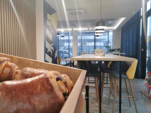 a dining room with a table and a table and some bread at Appart Hotel Odalys City Le Havre Centre in Le Havre