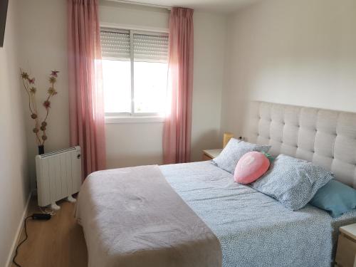 a bedroom with a bed with a pink pillow on it at Apartamento Gran Terraza in Moaña