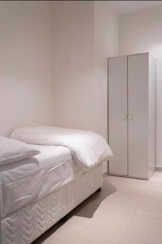 a white bedroom with a bed and a cabinet at شقة فاخرة في فندق العنوان ريزدينس Two bedrooms apartment at address residences in Sharm