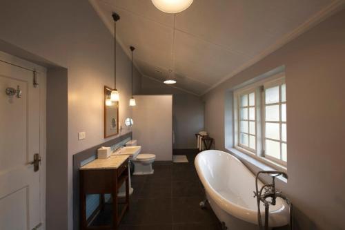 a bathroom with three sinks and a tub and two toilets at Ama Stays and Trails Tea Estate Bungalows , Munnar in Munnar