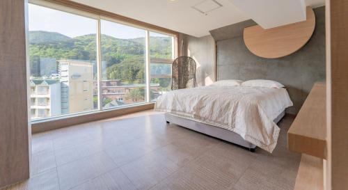a bedroom with a bed and a large window at Hinokki Haesuzzim Resort in Geoje 