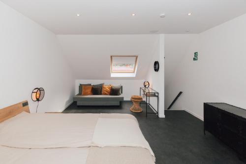 een witte slaapkamer met een bed en een bank bij Vakantiehuis Vélolit in Oudenaarde