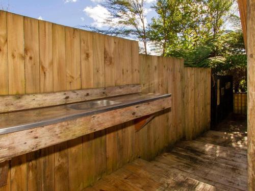 a wooden fence with a sink on top of it at Hosts on the Coast - Tairua Treehouse in Tairua