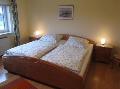 ein Bett in einem Schlafzimmer mit zwei Lampen an Tischen in der Unterkunft Ferienwohnungen Tenge in Hooksiel