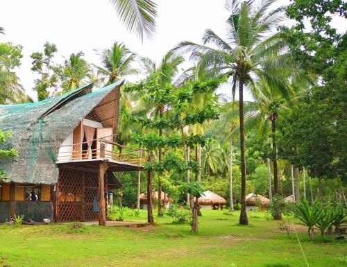 a resort with a thatched roof and palm trees at Playa Paraiso Nagtabon Beach in Bacungan