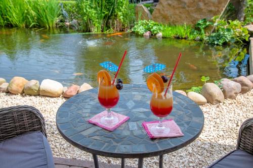 two drinks on a table next to a pond at Maarberg Resort in Schalkenmehren