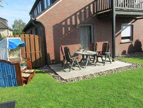 a patio with a table and chairs in a yard at Ferienwohnungen Tenge in Hooksiel