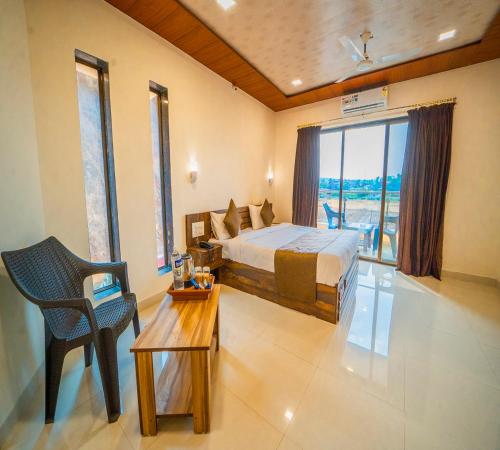a bedroom with a bed and a table and a chair at Vrindavan Resort in Mahabaleshwar