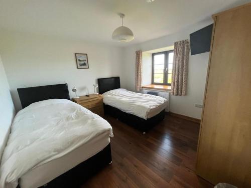a bedroom with two beds and a window at Berryhill East Steading - Sleeps 6 - Peterhead - Dog Friendly - Rural Location -Smart TV - Golf Driving Range - EV Point in Peterhead