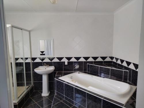 y baño con bañera y lavamanos. en Blue Owl Guest House, en Mossel Bay