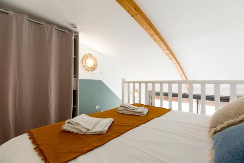 a bedroom with a bed with two towels on it at Appart'Hôtel Les Lofts du Grand Lac de Lozère in Langogne