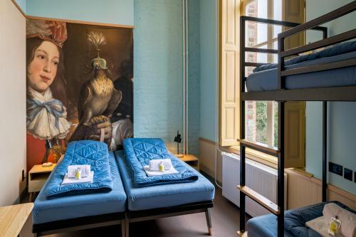 une chambre avec des lits superposés et une peinture d'une femme dans l'établissement Stayokay Hostel Domburg, à Oostkapelle
