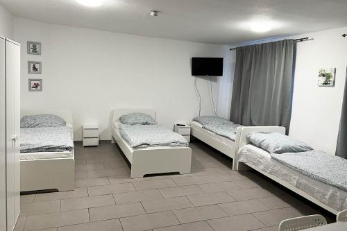 a room with three beds and a flat screen tv at work & stay apartment in Eitorf