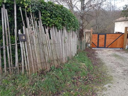 a wooden fence with a gate and a driveway at Gîte zen dans les bois in Blésignac